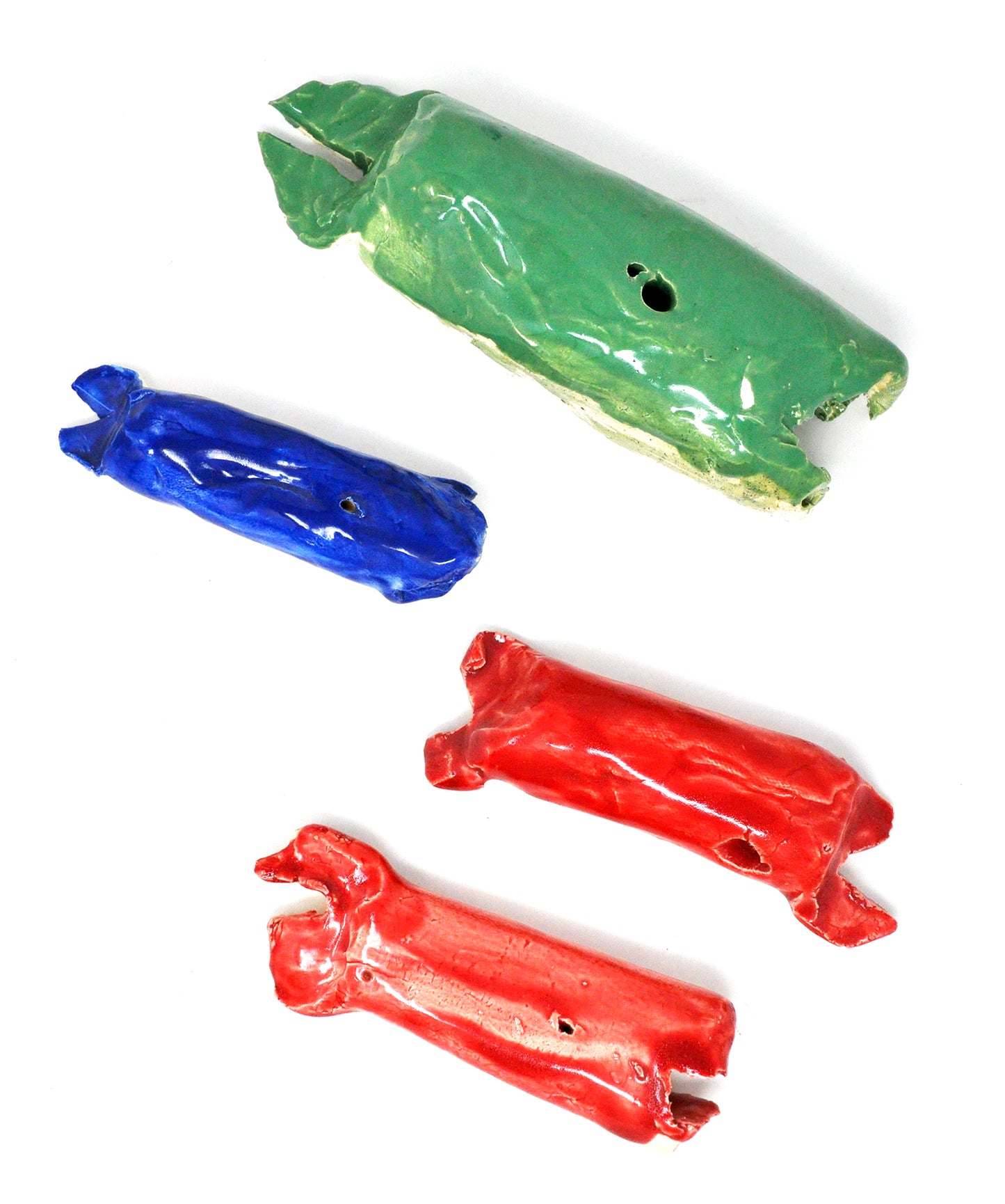 Four ceramic whales. The largest is green, and then there are two red whales and one blue whale that are approximately the same size. 