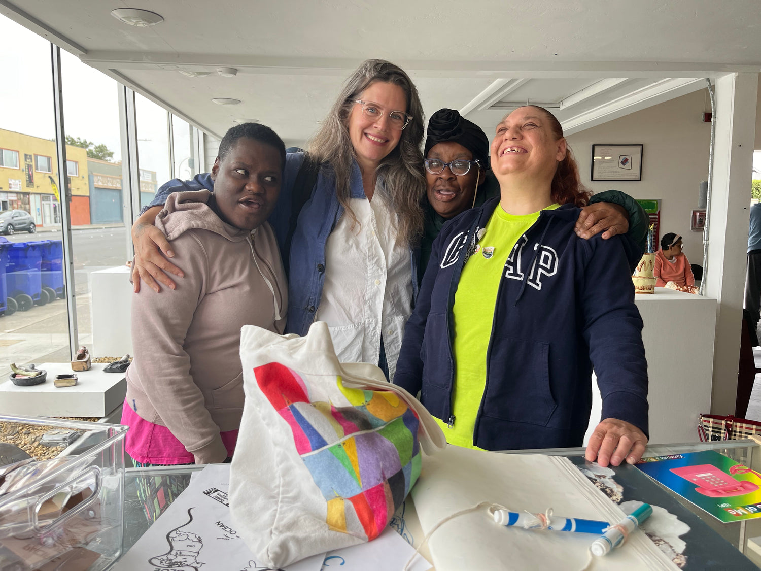 Photo of NIAD artists Shantae Robinson, Felicia Griffin, and Heather Copus with NIAD Development Director Rebecca Teague smiling in NIAD's Annex Gallery.