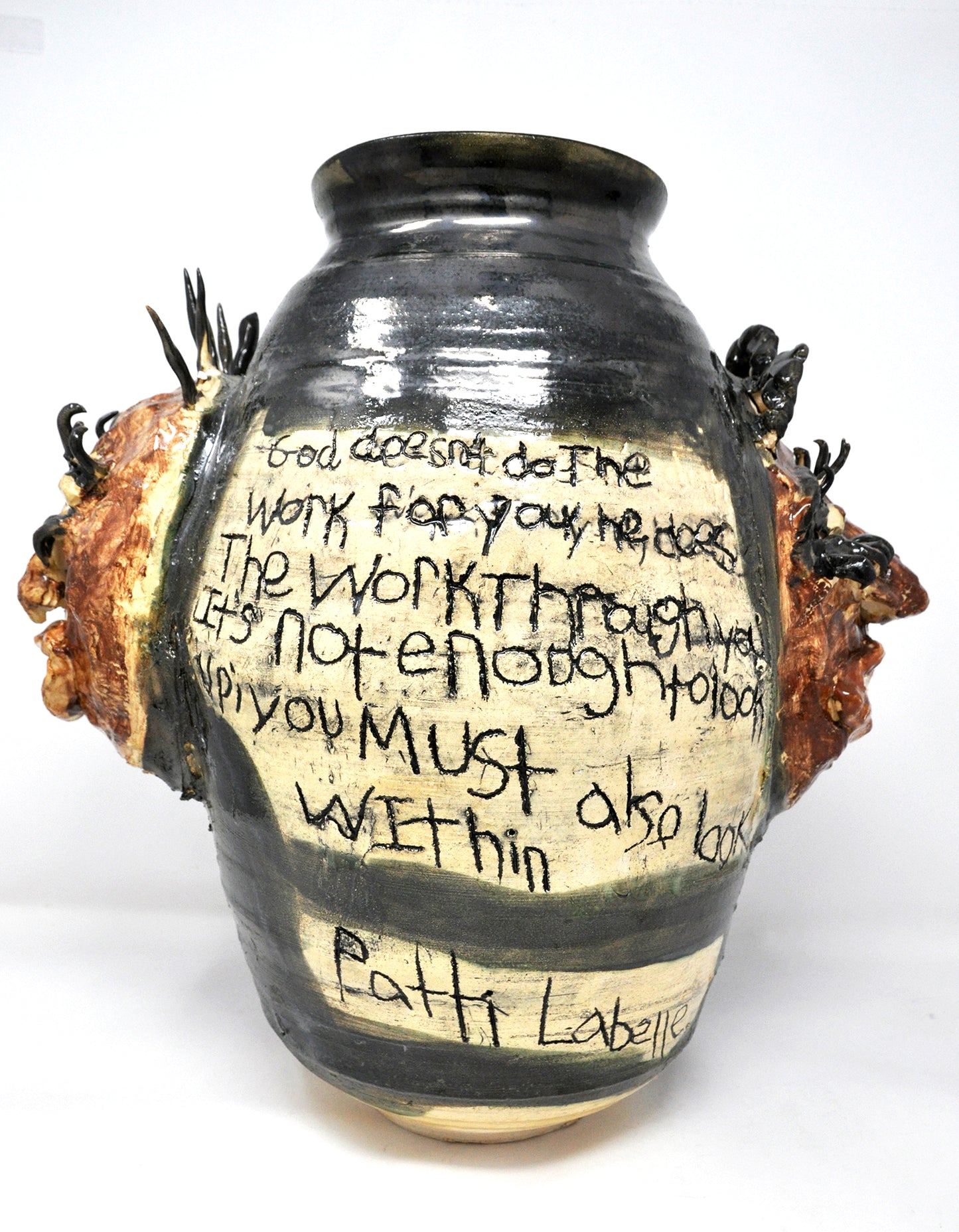 Back view of the Patti Labelle Vessel. Two faces are visible in profile on either side of the vessel. A hand-incised inscription reads centered on the piece reads: “God doesn’t do the work for you. He does the work through you. It’s not enough to look up, you must also look within. Patti Labelle.”